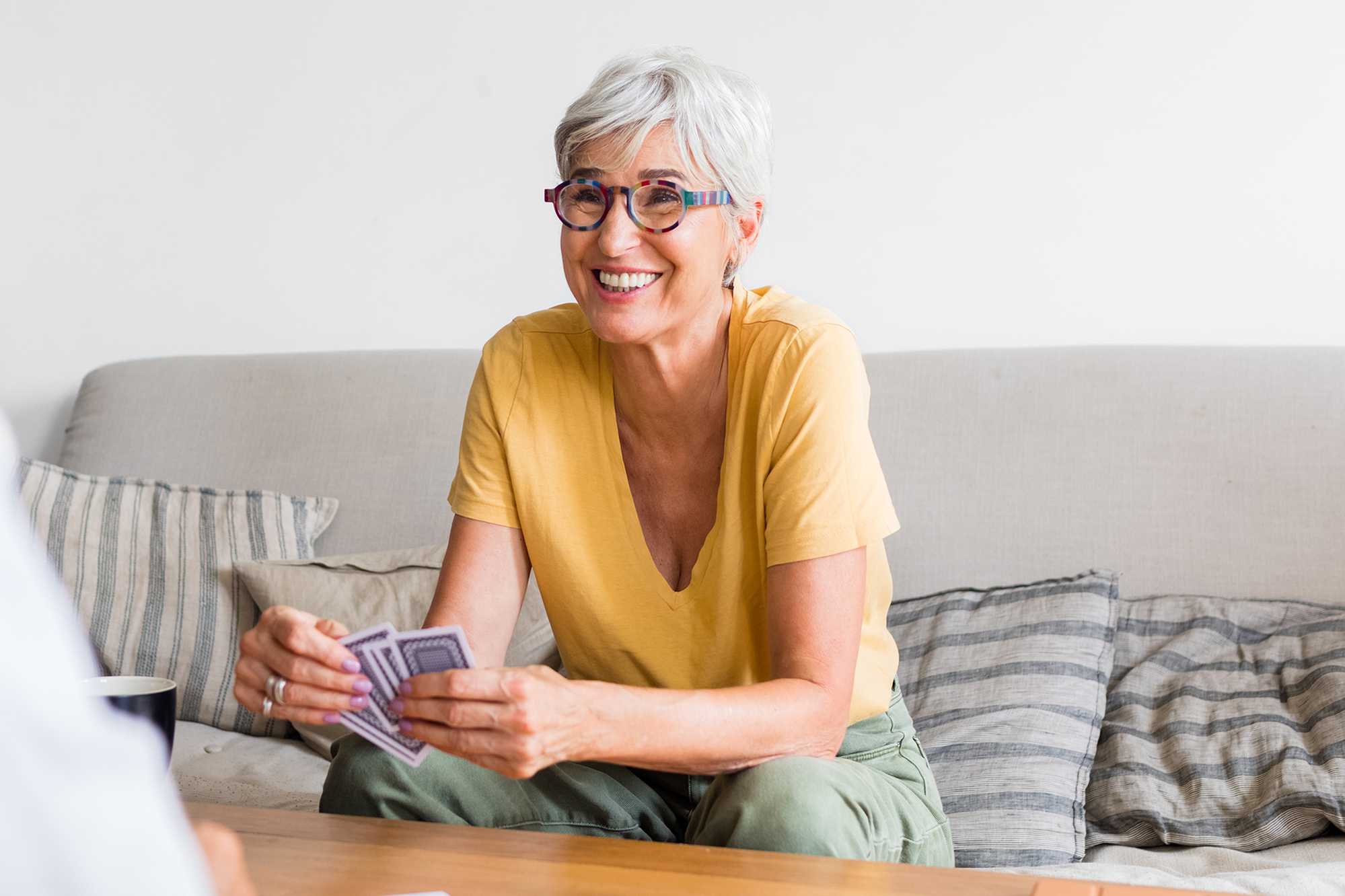 Older woman playing cards while sitting on couch